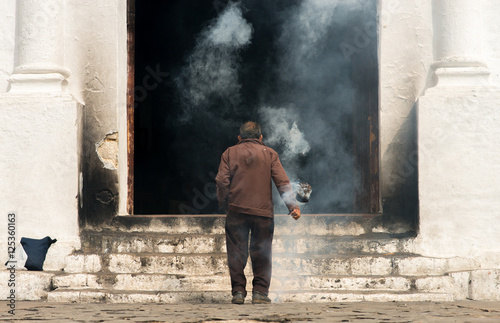 Mayan man performing a ritual in front of the church in the town of Chichicastenango, Guatemala photo