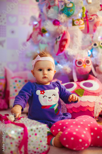The beautiful baby sits near gifts