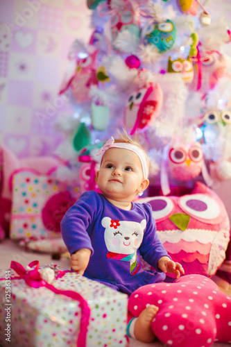 The beautiful baby sits  near gifts
