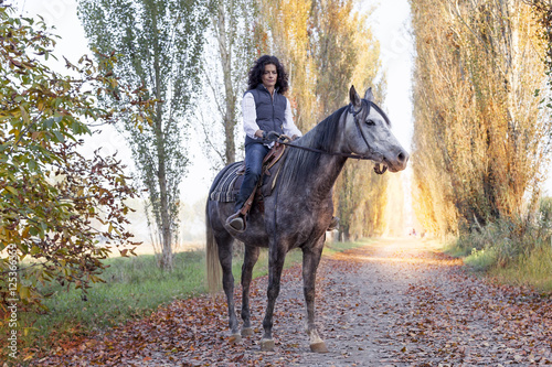 Obraz na plátně horsewoman rides his horse to the country roads in autumn
