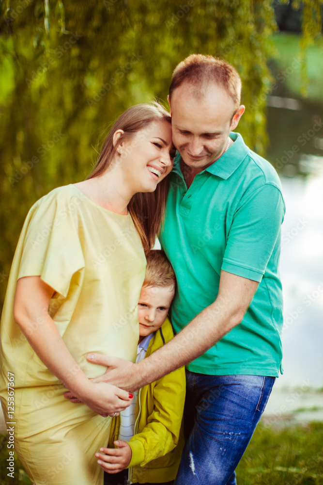 Beautiful pregnant woman with her husband and son outside Beautiful pregnant woman with her husband and son outside