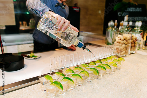 Fototapeta Naklejka Na Ścianę i Meble -  Bartender pours tequila in a glass. Selective focus.