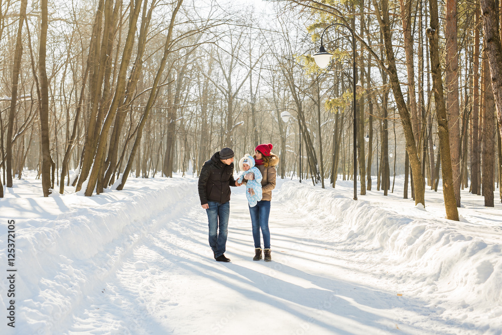 parenthood, season and people concept - happy family with child in winter clothes outdoors