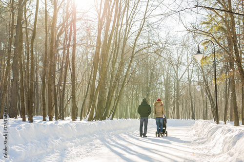 Father and mother with baby carriage in winter forest