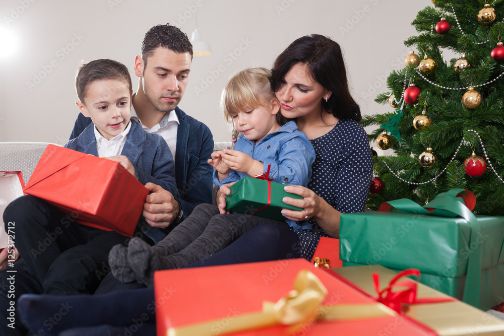 family unboxing christmas presents in front of christmas tree family unboxing christmas presents in front of christmas tree