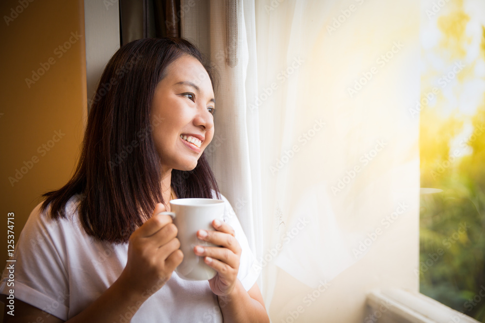 Asian girl hold cup of coffee relaxing look outside window Asian girl hold cup of coffee relaxing look outside window