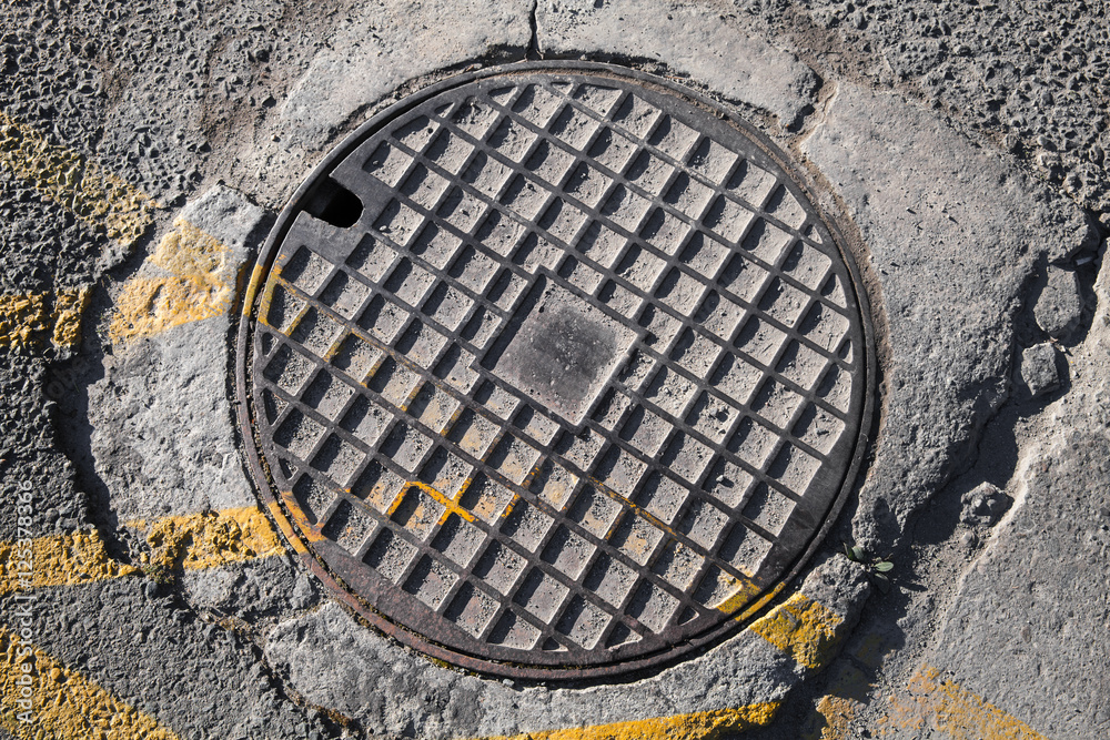 Round metal hatch in urban pavement