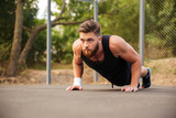 Attractive bearded sportsman doing push-ups outdoors