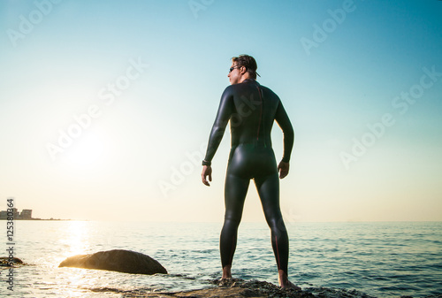 Man in diving suit standing in waves