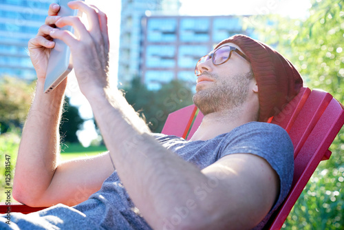 Hipster guy in park websurfing on digital tablet