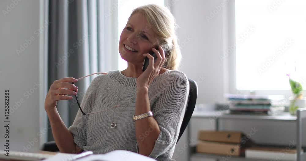 Mature business woman working on desktop computer and smartphone