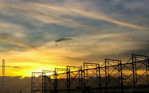 Silhouette of scaffolding in the construction site before to night time or sunset time. worker empty. Building under construction and the construction crane or power crane.