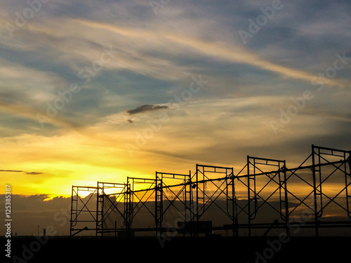 Silhouette of scaffolding in the construction site before to night time or sunset time. worker empty. Building under construction and the construction crane or power crane.