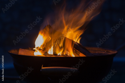 Firewood burning in grill bowl at night