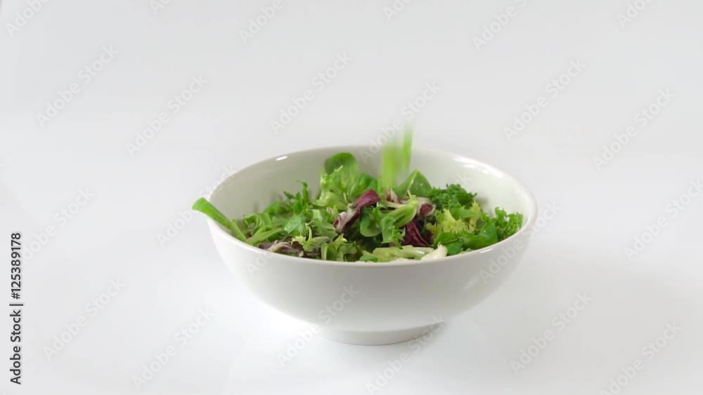 fresh green salad falling into a bowl. slow motion isolated on white fresh green salad falling into a bowl. slow motion isolated on white