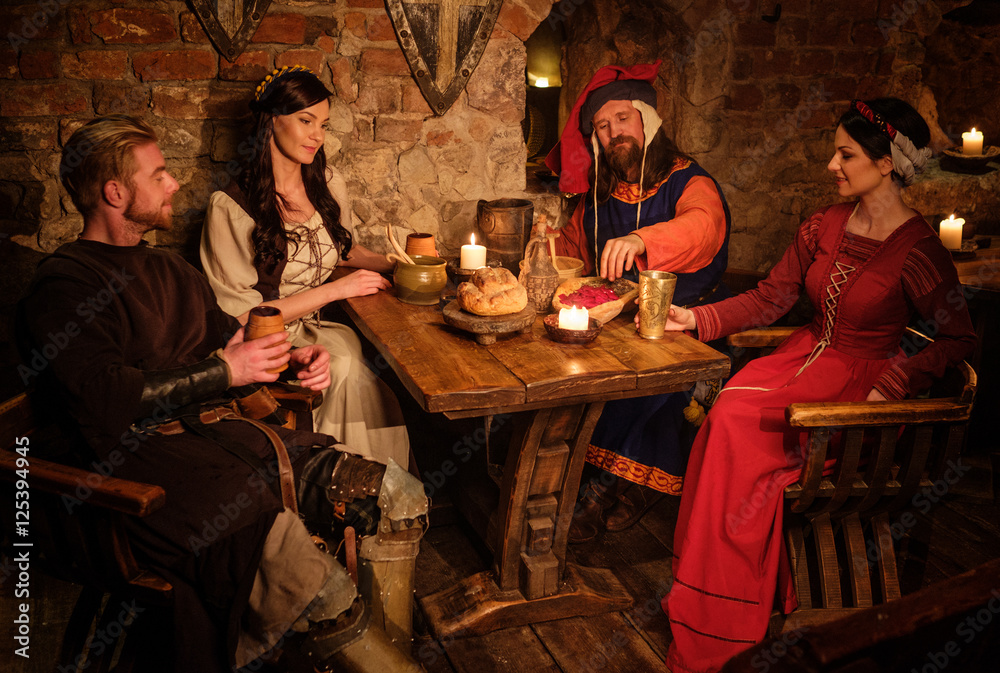 Medieval people eat and drink in ancient castle tavern