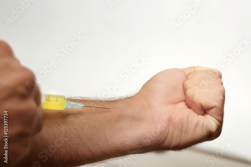 Muscular man injecting steroids on light background, closeup
