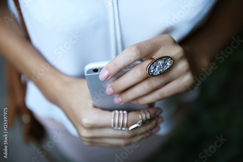 Female hands with phone and stylish rings, closeup