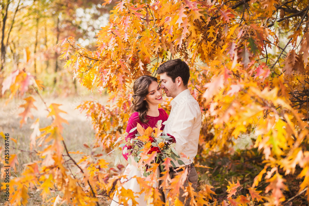 Stylish and romantic caucasian couple in beautiful autumn park. Love, relationships, romance, happiness concept. Bouquet in girl's hands. Stylish and romantic caucasian couple in beautiful autumn park. Love, relationships, romance, happiness concept. Bouquet in girl's hands.