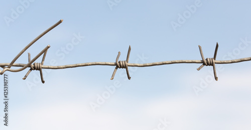 Barbed wire on a wooden post against blue sky