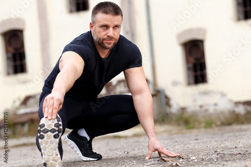 Portrait of a man stretching before running.