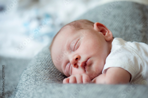 Newborn baby boy lying on bed, sleeping, close up