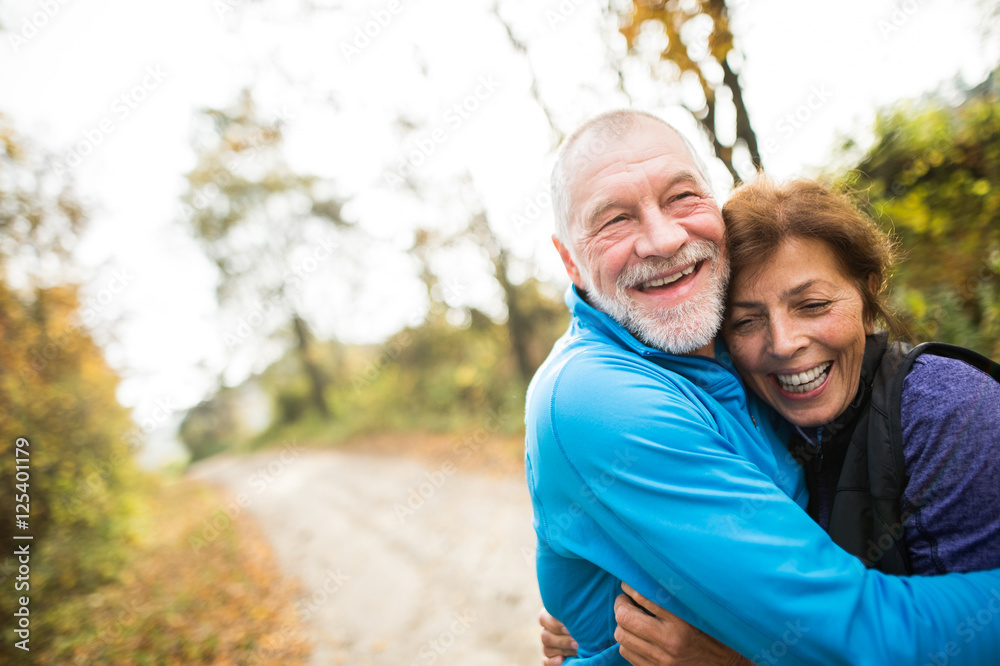 Beautiful senior couple running outside in sunny autumn forest Beautiful senior couple running outside in sunny autumn forest