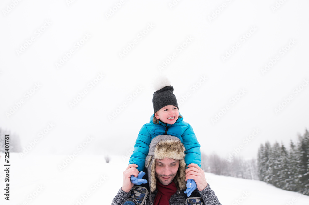 Father giving his son piggyback. Winter nature.