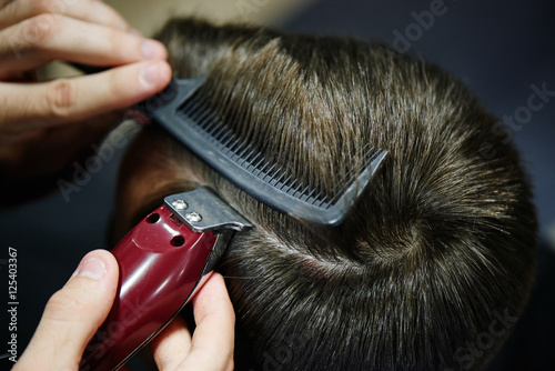 The Barber makes the man parted the customer an electric trimmer in a Barbershop