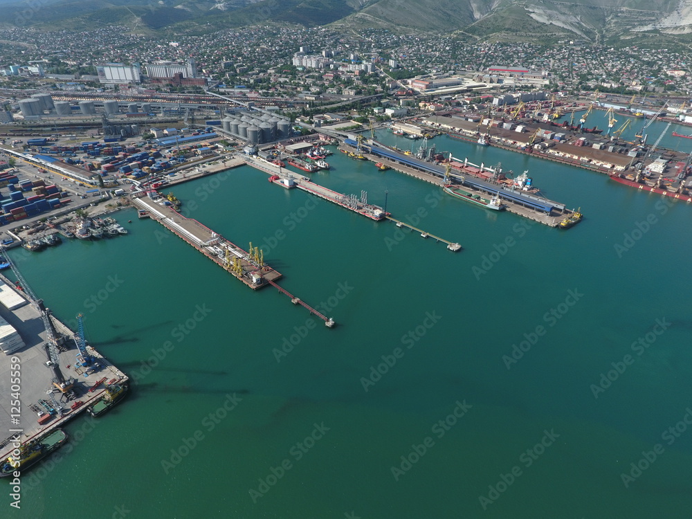 Industrial seaport, top view. Port cranes and cargo ships and barges. Loading and shipment of cargo at the port. View of the sea cargo port with a bird's eye view