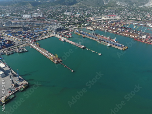 Industrial seaport, top view. Port cranes and cargo ships and barges. Loading and shipment of cargo at the port. View of the sea cargo port with a bird's eye view