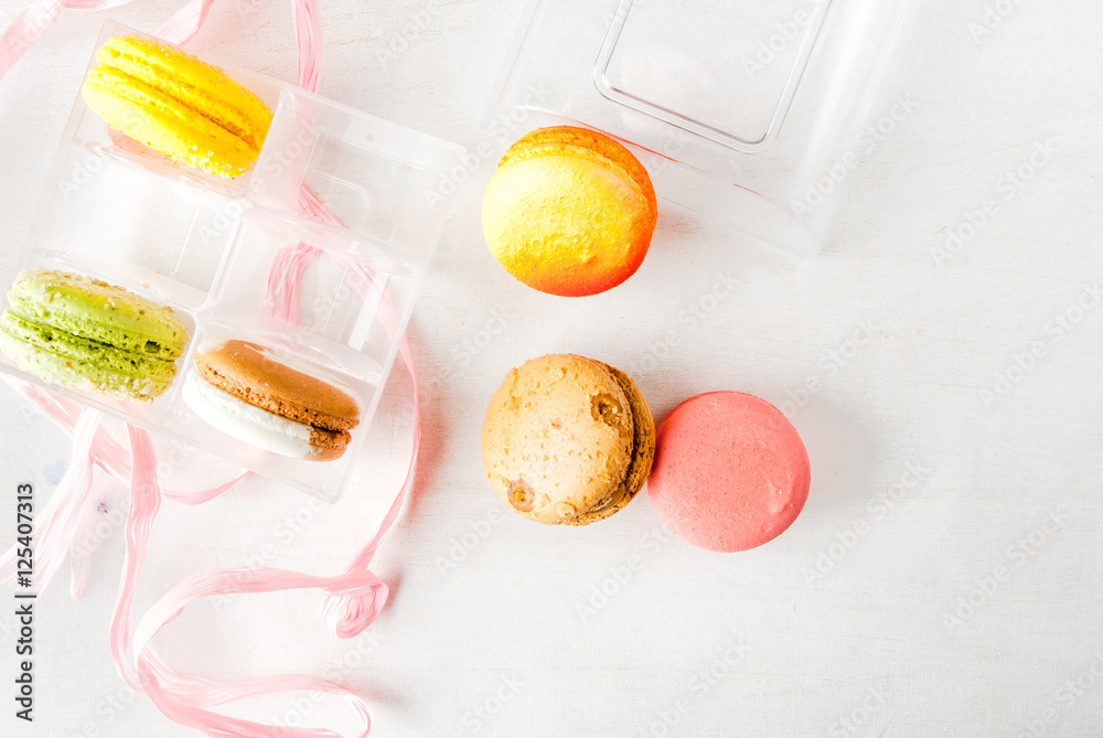 Open a transparent gift box with cakes macarons on a white wooden table. Top view, copy space Open a transparent gift box with cakes macarons on a white wooden table. Top view, copy space