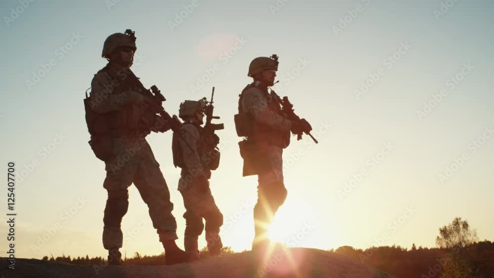 Squad of Three Fully Equipped and Armed Soldiers Standing on Hill in Desert Environment in Sunset Light. Slow Motion.