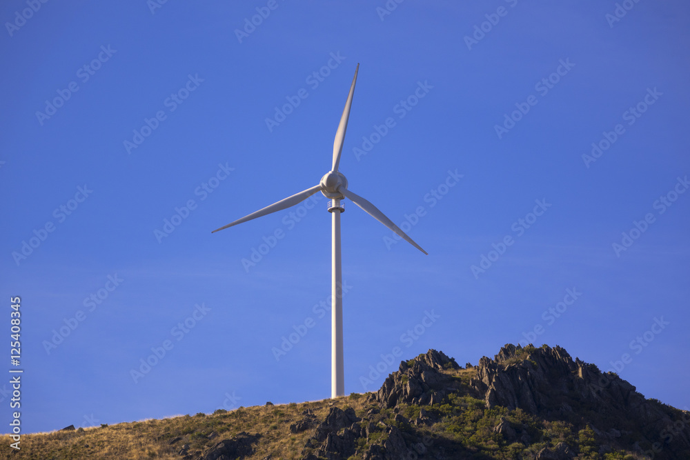 Electric generators located in countryside with beautiful landscape on background, wind turbines against cloudy sky and sun rays, alternative energy resources Electric generators located in countryside with beautiful landscape on background, wind turbines against cloudy sky and sun rays, alternative energy resources