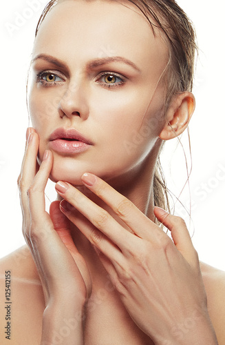 Close-up beauty face of young blonde woman with hands near chin, natural lips and make-up over white background