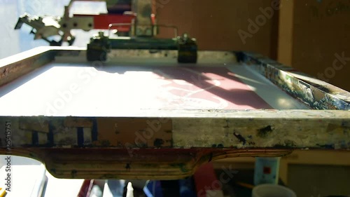 Traditional silk-screen printing preparation - artist inserts blank paper and places black ink on top of the screen