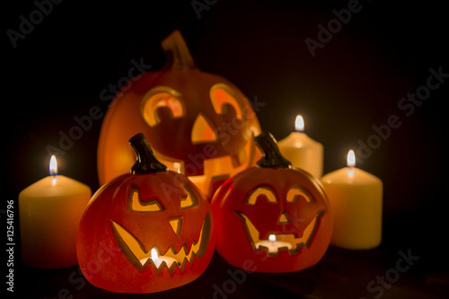 Spooky Halloween scene with Jack-o-Lanterns and candles glowing on a black background
