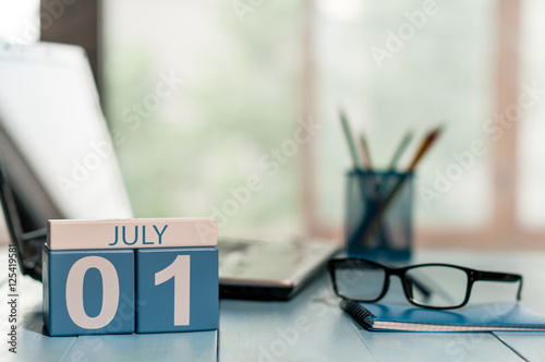 July 1st. Day of the month 1 , wooden color calendar on business workplace background. Summer concept. Empty space for text