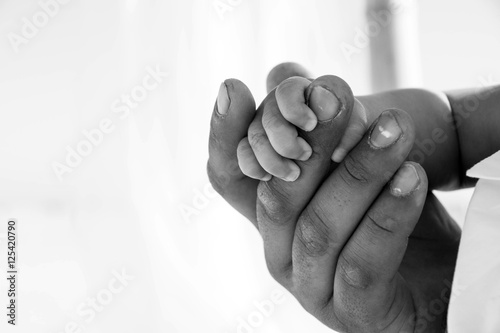 Dad is holding baby hand. Black and white photo