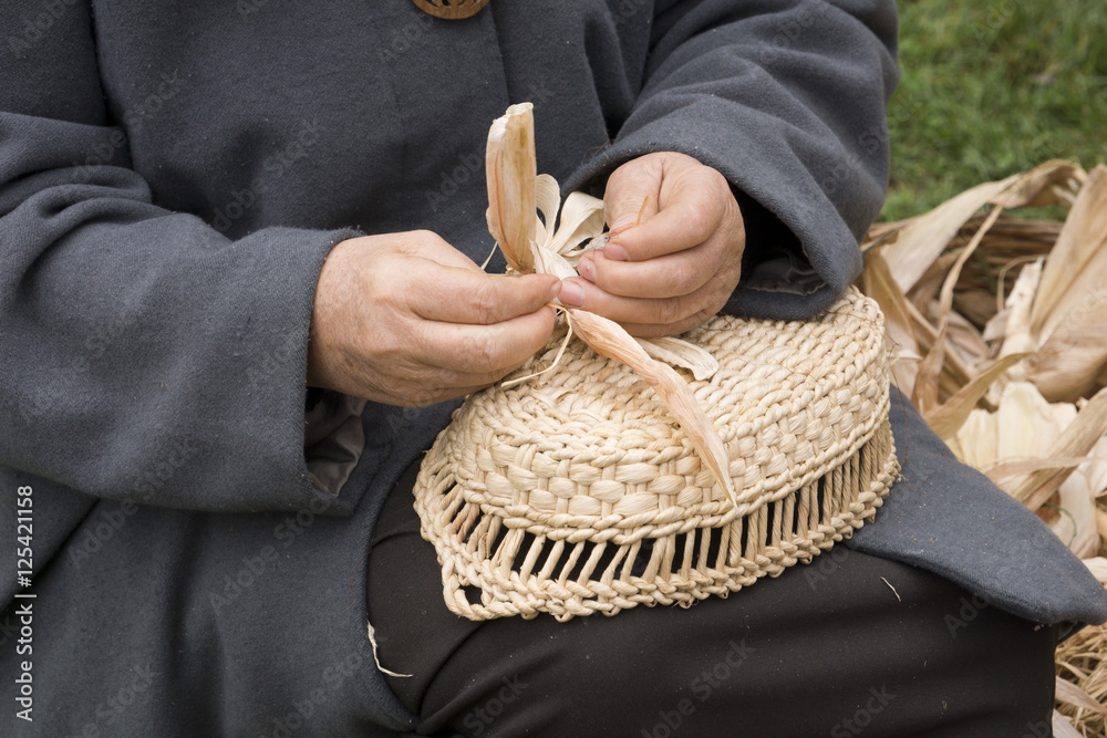 Old woman making a corn husk doll