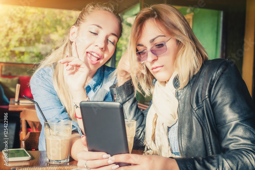 Two girlfriends having fun with digital tablet