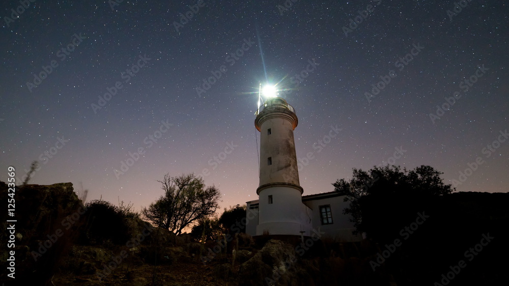 Timelapse of beautiful night landscape with lighthouse with rotating starry sky on a background