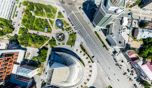 Aerial city view with crossroads, roads, houses, buildings, parks and parking lots. Copter drone helicopter shot. Panoramic wide angle image.