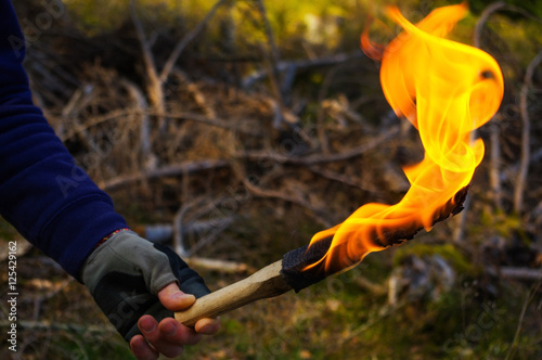 part of a man and hand with torch flame in wild nature background.