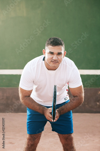 Handsome young man on tennis court. Man playing tennis. Man is ready to hit tennis ball