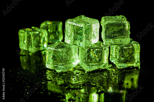 ice cubes in green light on a black table.
