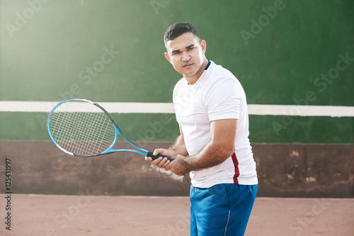Handsome young man on tennis court. Man playing tennis. Man is ready to hit tennis ball © kleberpicui