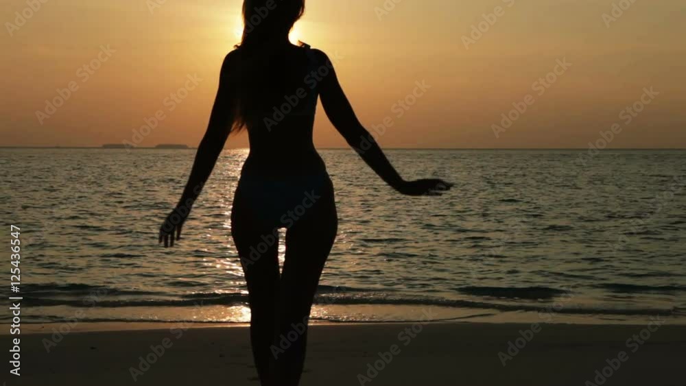 Silhouette of the woman against a sunset at ocean Silhouette of the woman against a sunset at ocean