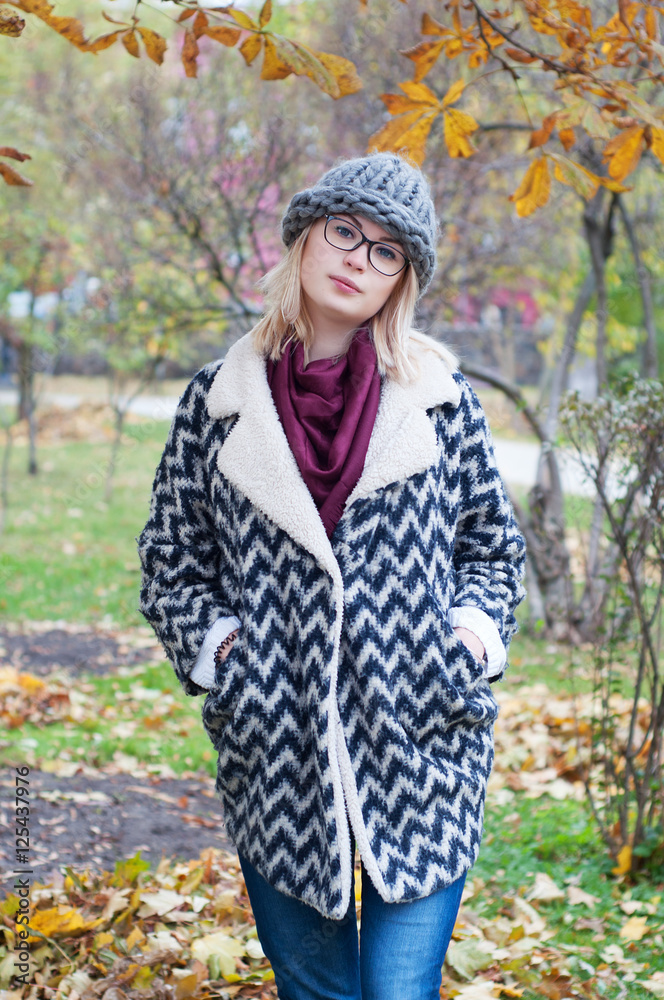 Student girl in park wearing warm cardigan and knitted hat Student girl in park wearing warm cardigan and knitted hat