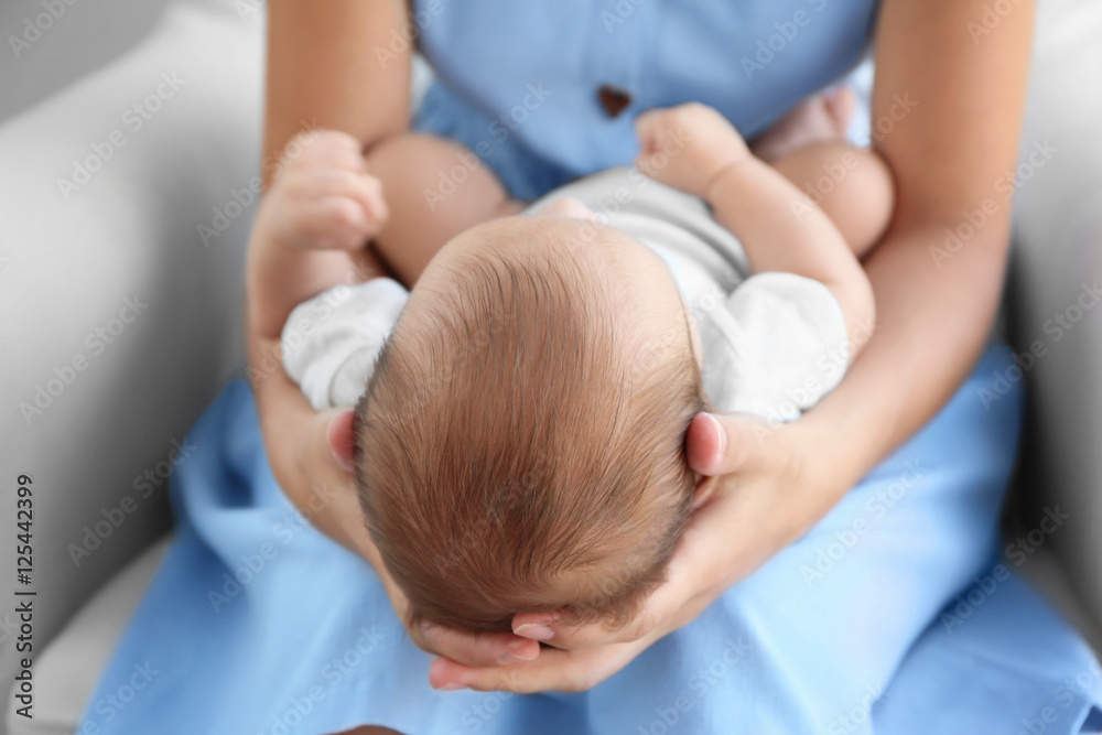 Fototapeta premium Mother holding cute baby on her knees, close up view